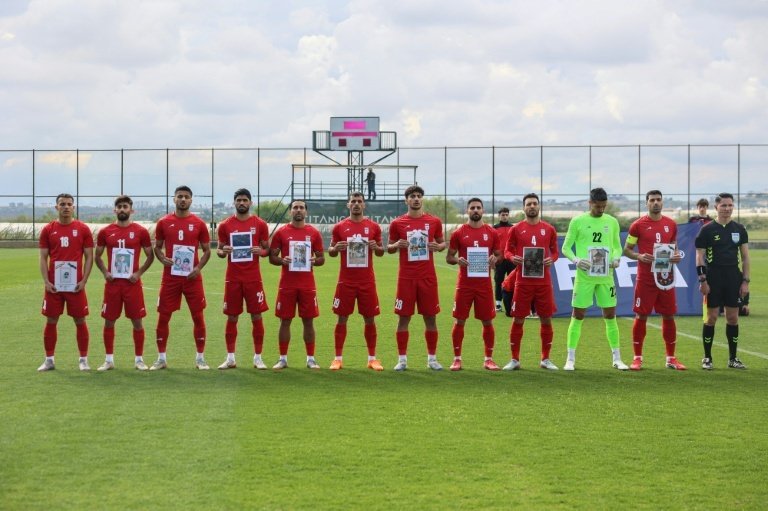 Des joueurs iraniens brandissent une photo d'enfants qui auraient été tués lors de la guerre au Moyen-Orient. AFP