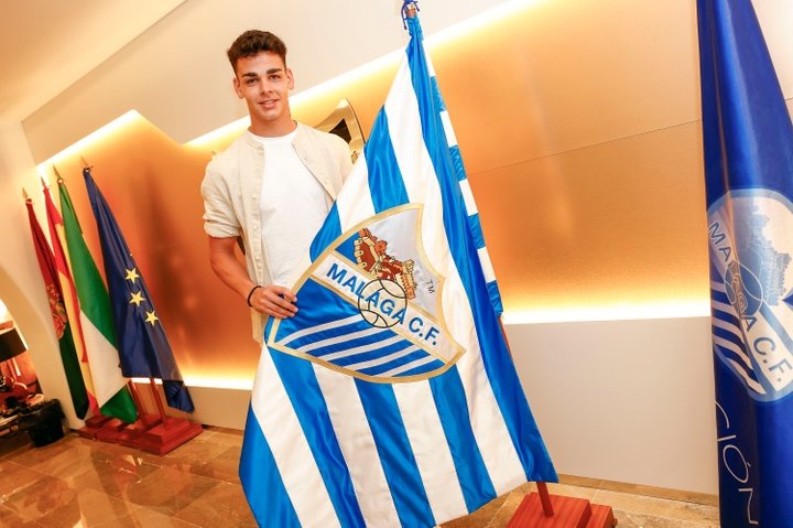 Andrés Caro posa con la bandera del Málaga CF tras su firma de renovación. Málaga CF