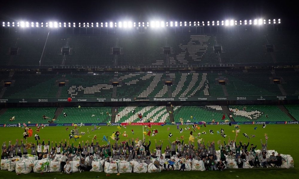 Los voluntarios del Real Betis posan con los 14.000 peluches recogidos en el descanso del Real Betis-Athletic Club.- RBB