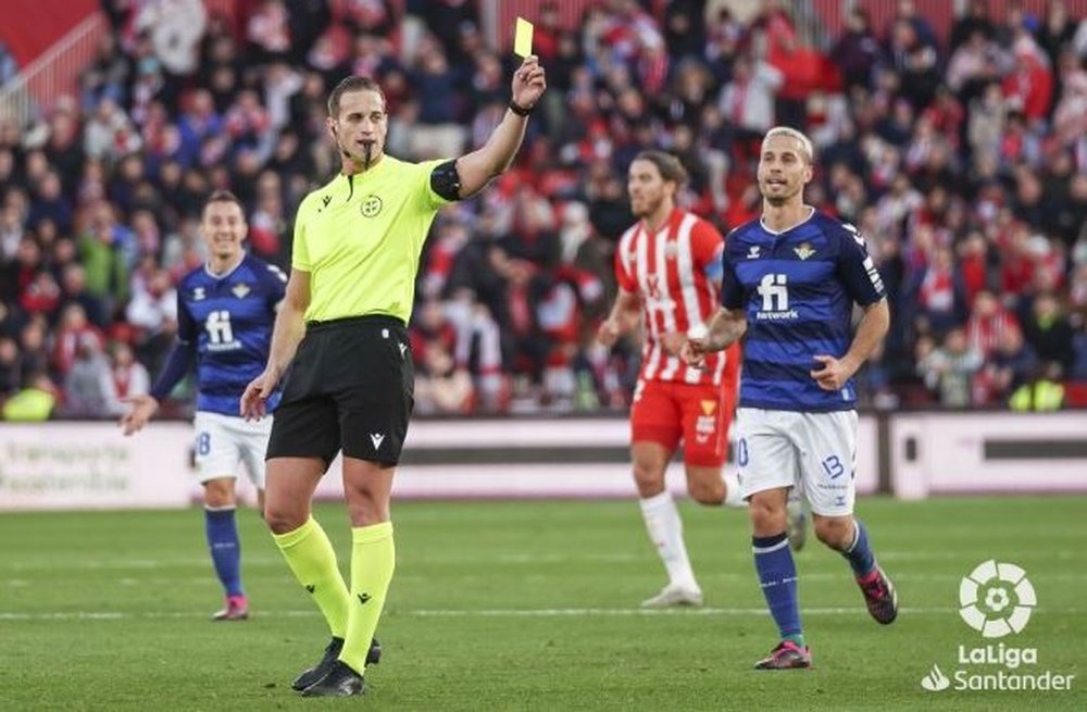 Javier Alberola Rojas, árbitro del Almería-Real Betis, muestra una tarjeta amarilla en presencia de Canales.- LaLiga