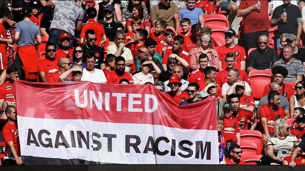 Aficionados del Manchester United desplegan una pancarta para apoyar a Paul Pogba. Captura/DAZN