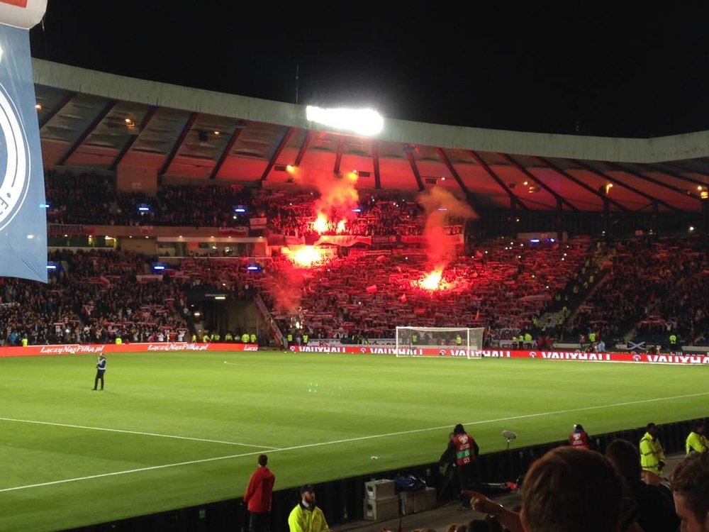 Aficionados polacos encienden bengalas antes del inicio del partido clasificatorio para el Europeo de Francia en Escocia. Twitter