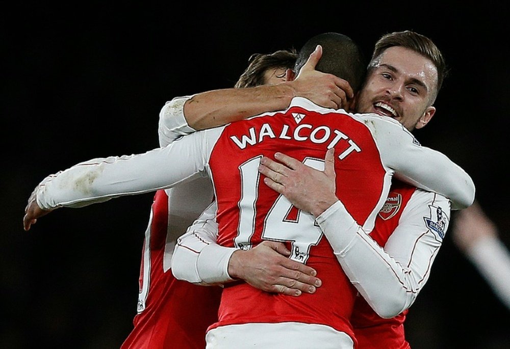 Arsenals midfielder Theo Walcott (C) celebrates with Aaron Ramsey (R) after scoring his teams first goal during the match against Manchester City at the Emirates Stadium in London on December 21, 2015