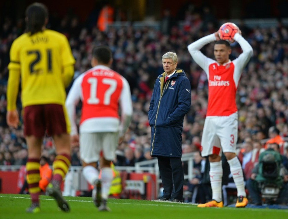Arsenal manager Arsene Wenger (2L) watches as defender Kieran Gibbs prepares to take a throw-in during the FA Cup fourth round match against Burnley at the Emirates Stadium in London, on January 30, 2016