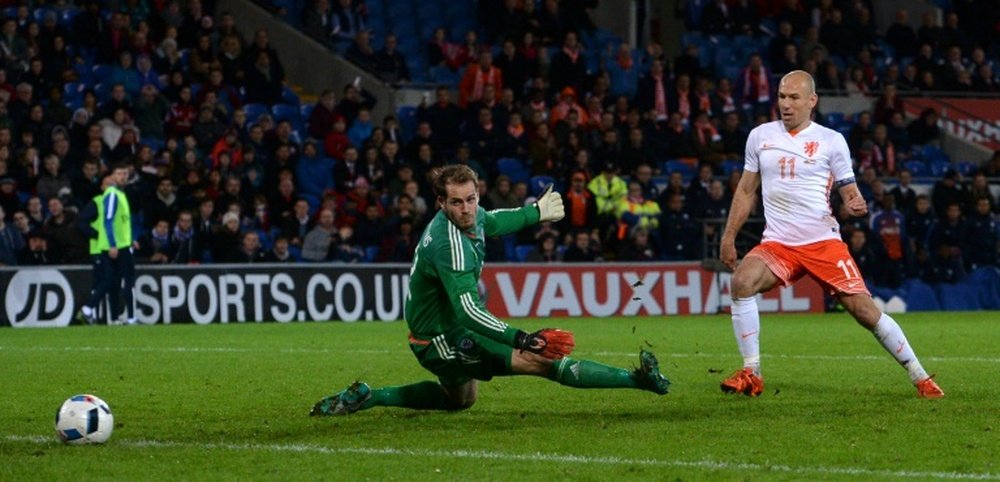 Netherlands midfielder Arjen Robben (R) slots the ball past Waless goalkeeper Owain Fon Williams (L) to score Netherlands third goal during the international friendly football match in south Wales on November 13, 2015