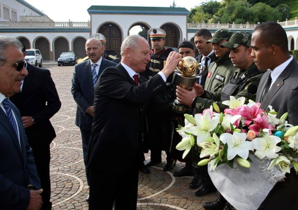 Etoile du Sahels club President Ridha Charfeddine (C) offers flowers before giving the Confederation of African Football trophy to presidential guards on December 2, 2015 at Carthage Palace in Tunis