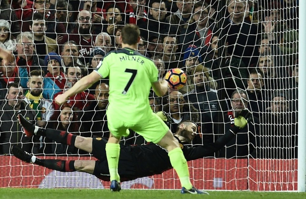Liverpools idfielder James Milner (R) shoots from the penalty spot to score his teams first goal during the English Premier League football match between Manchester United and Liverpool on January 15, 2017