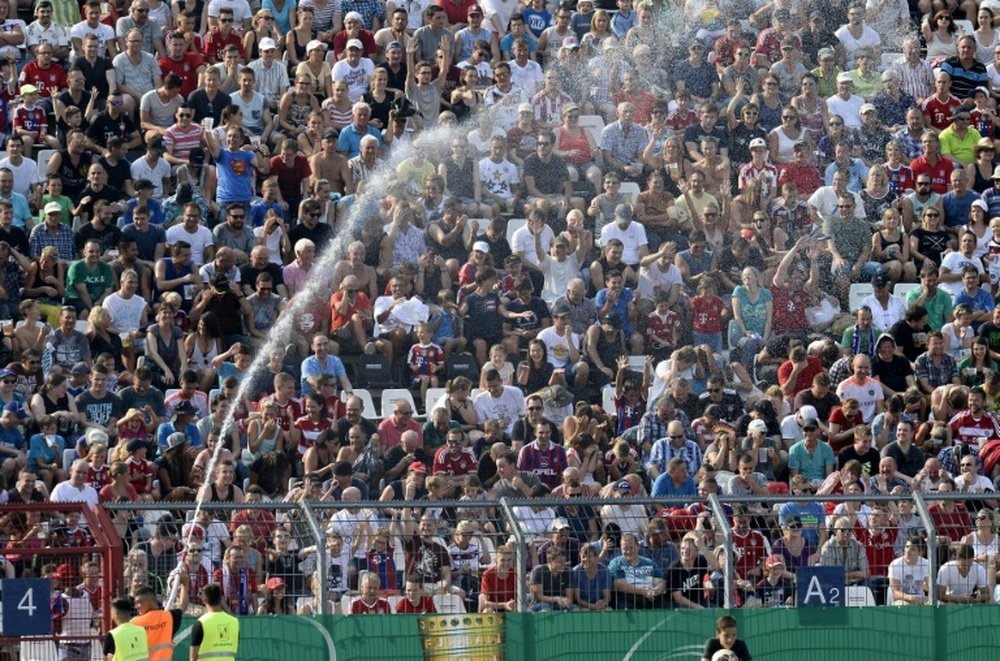 A steward cools spectators with water during the German Cup first round tie between Noettingen and Bayern Munich in Karlsruhe on August 9, 2015