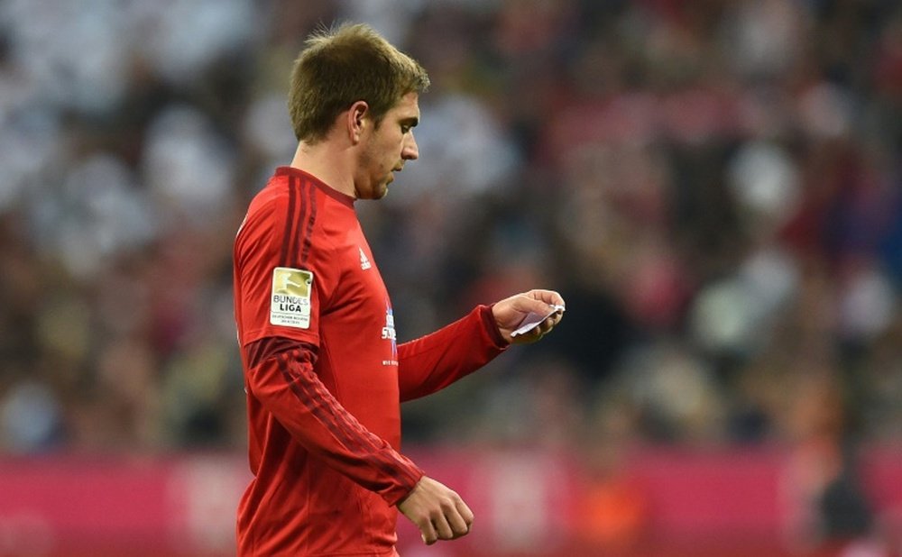 Bayern Munichs defender Philipp Lahm reads a note from Bayern Munichs Spanish headcoach Pep Guardiola during the German first division Bundesliga football match FC Bayern Munich vs FC Ingolstadt 04 in Munich, southern Germany, on December 12, 2015