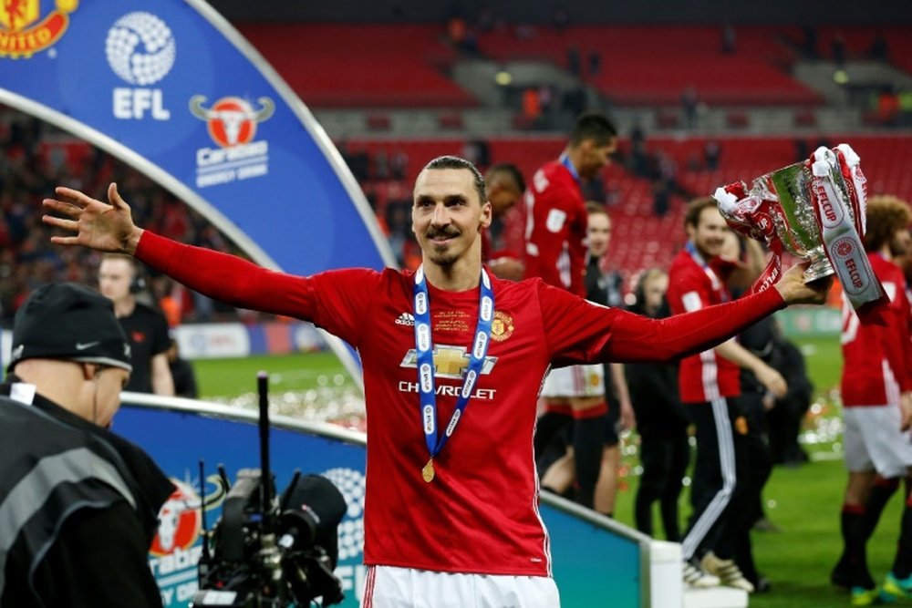 Manchester United's Zlatan Ibrahimovic celebrates with the trophy on the pitch. AFP