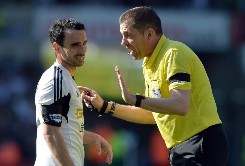 Referee Phil Dowd speaks to Swansea Citys English midfielder Leon Britton (L) during an English Premier League football match in Swansea on April 13, 2014