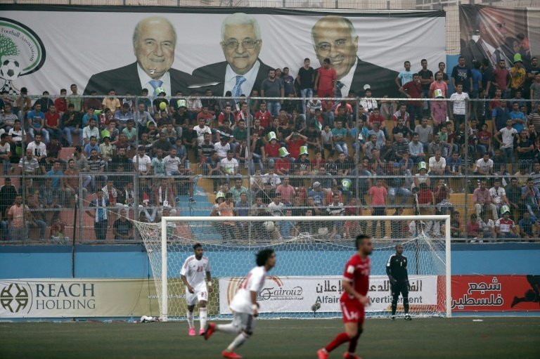A banner bearing portraits of Palestinian president Mahmud Abbas (C), outgoing FIFA president Sepp Blatter (L) and Palestinian federation president Djibril Rajoub at the World Cup qualifier at in the West Bank town of Al-Ram on September 8, 2015