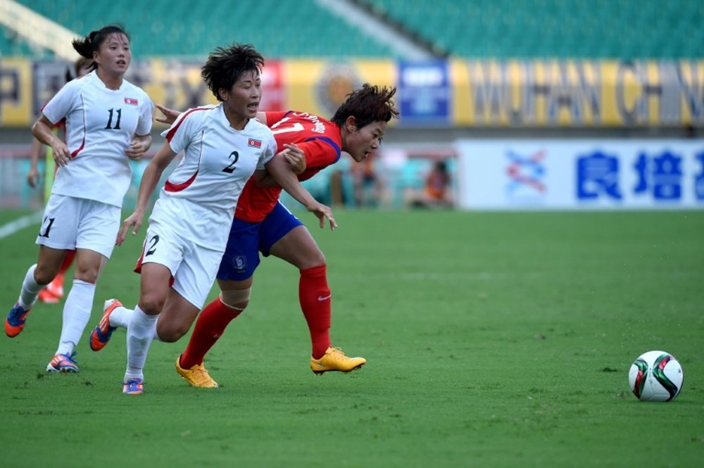 Lee Hyun Young (right) of South Korea fights for the ball with North Koreas Yun Song Mi (centre) during their womens East Asian Cup match at in Wuhan on August 8, 2015