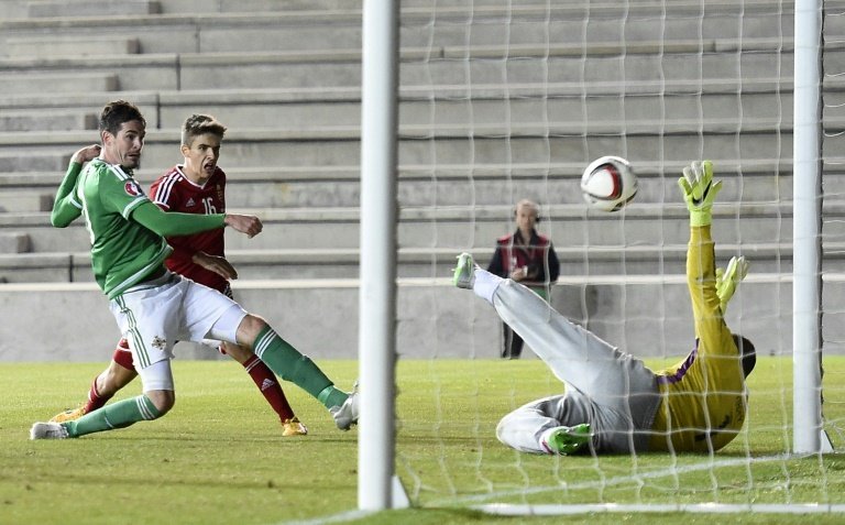 Northern Irelands striker Kyle Lafferty (L) shoots to score their late equaliser past Hungarys goalkeeper Gabor Kiraly (R) during the Euro 2016 qualifying group F football match in Belfast on September 7, 2015