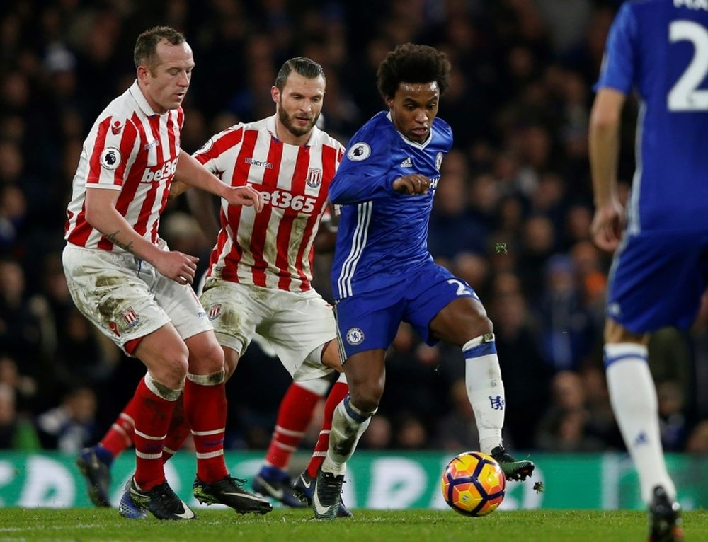 Chelseas midfielder Willian vies with Stoke Citys midfielder Charlie Adam (L) and Stoke Citys defender Erik Pieters (2nd L) during the English Premier League football match at Stamford Bridge in London on December 31, 2016