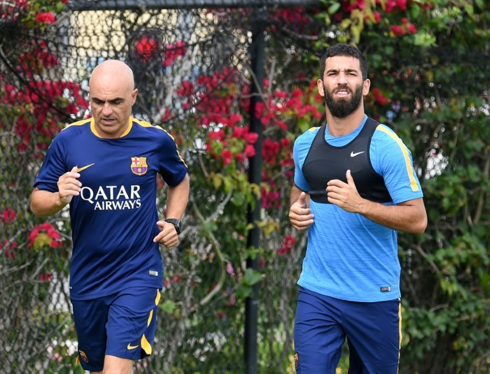 Barcelonas new player Arda Turan (R) runs with a trainer during a light training session at the StarHub Stadium in Carson, California, on July 20, 2015