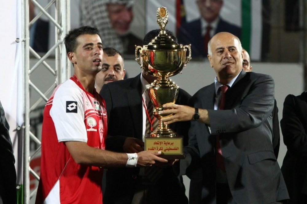 Jibril Al Rajoub (R), President of Palestinian Football Association, gives the trophy to Fadi Dweik, the captain of Hebrons Al-Ahly, after they won the Palestine Cup final against Gaza Strips Shejaiya on August 14, 2015