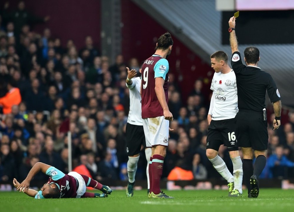 Evertons midfielder James McCarthy (2nd R) receives a yellow card from referee Paul Tierney for a foul on West Ham Uniteds midfielder Dimitri Payet (L) during the English Premier League football match in Upton Park, east London on November 7, 2015