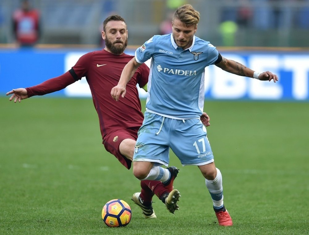 Romas midfielder from Italy Daniele De Rossi (L) tackles Lazios forward from Italy Ciro Immobile during the Italian Serie A football match SS Lazio vs AS Roma on December 4, 2016