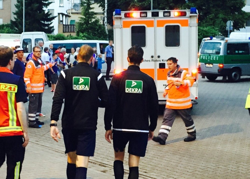 Martin Petersen (centre left) makes his way to an ambulance for a check up after being hit by a lighter Osnabrucks German Cup game against Leipzig in Osnabruck on August 10, 2015