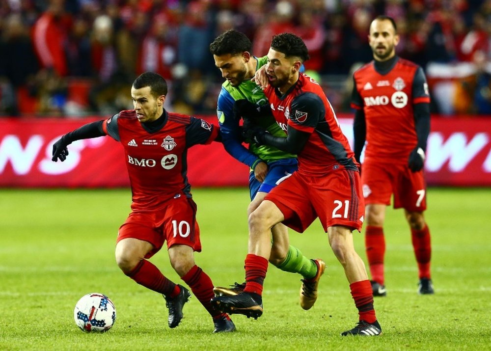 Sebastian Giovinco (L) and Jonathan Osorio of Toronto FC fight off a challenge from Cristian Roldan of the Seattle Sounders during the 2017 MLS Cup Final