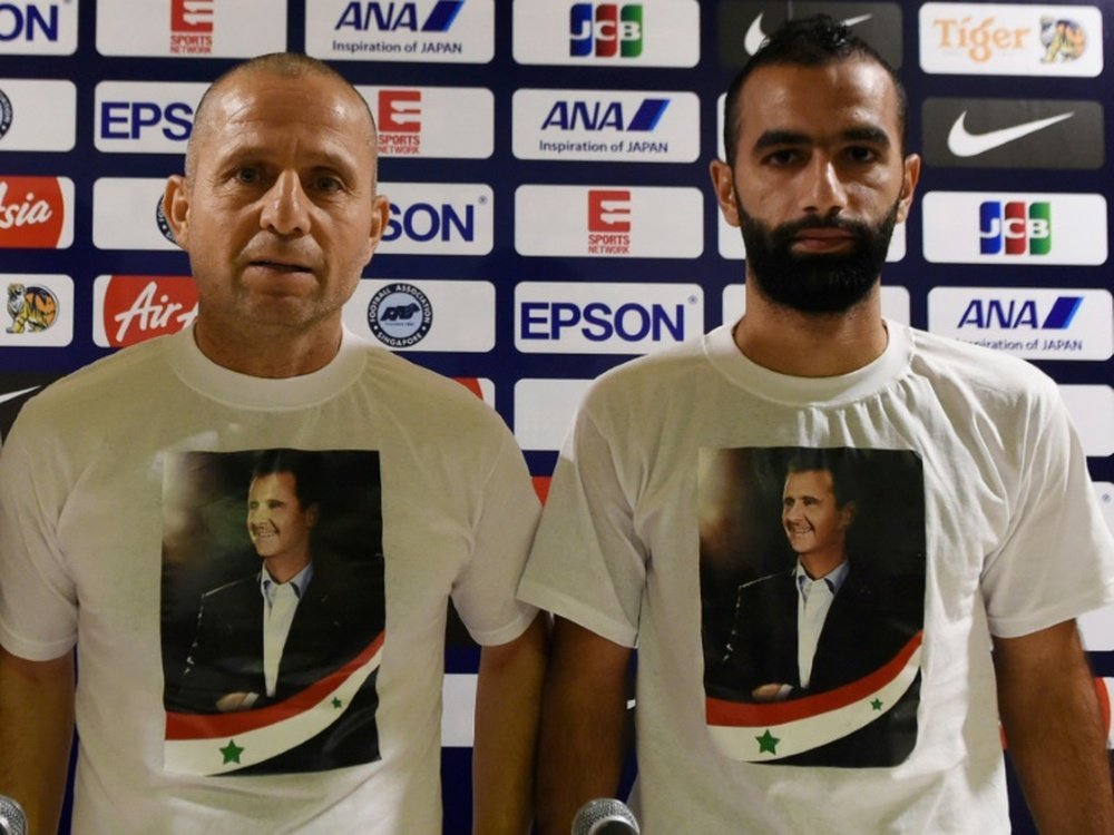 Syrias head coach Fajr Ibrahim (L) and footballer Osama Omari pose with a shirt bearing the portrait of Syrian President Bashar al-Assad ahead of a World Cup qualifier in Singapore
