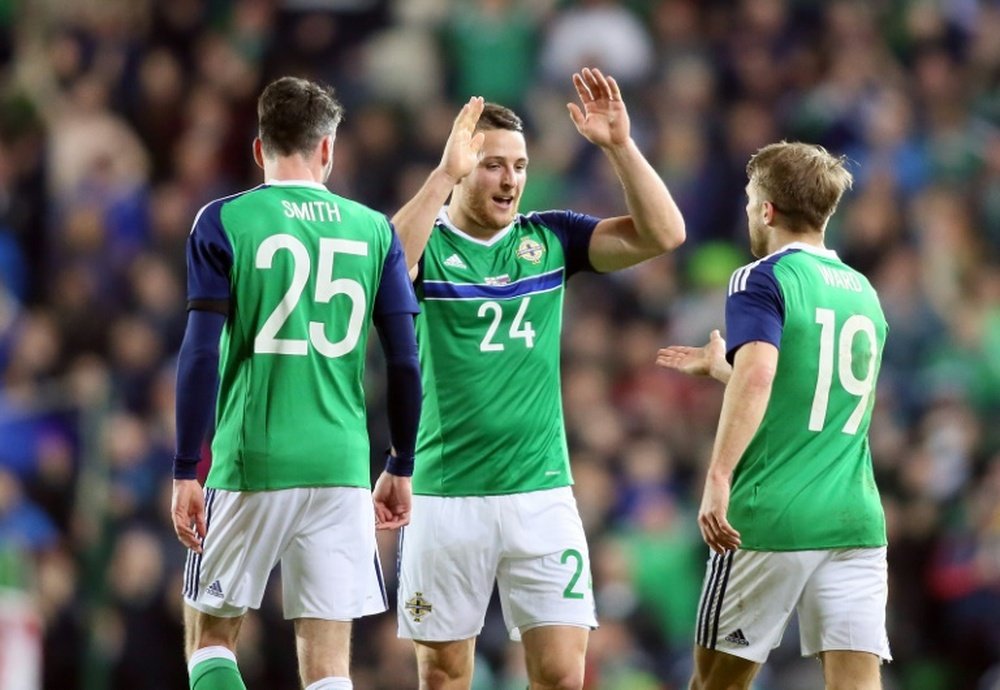 Northern Irelands striker Conor Washington (C) celebrates with defender Michael Smith (L) and striker Jamie Ward (R) after scoring the opening goal of the international friendly football match against Slovenia on March 28, 2016.