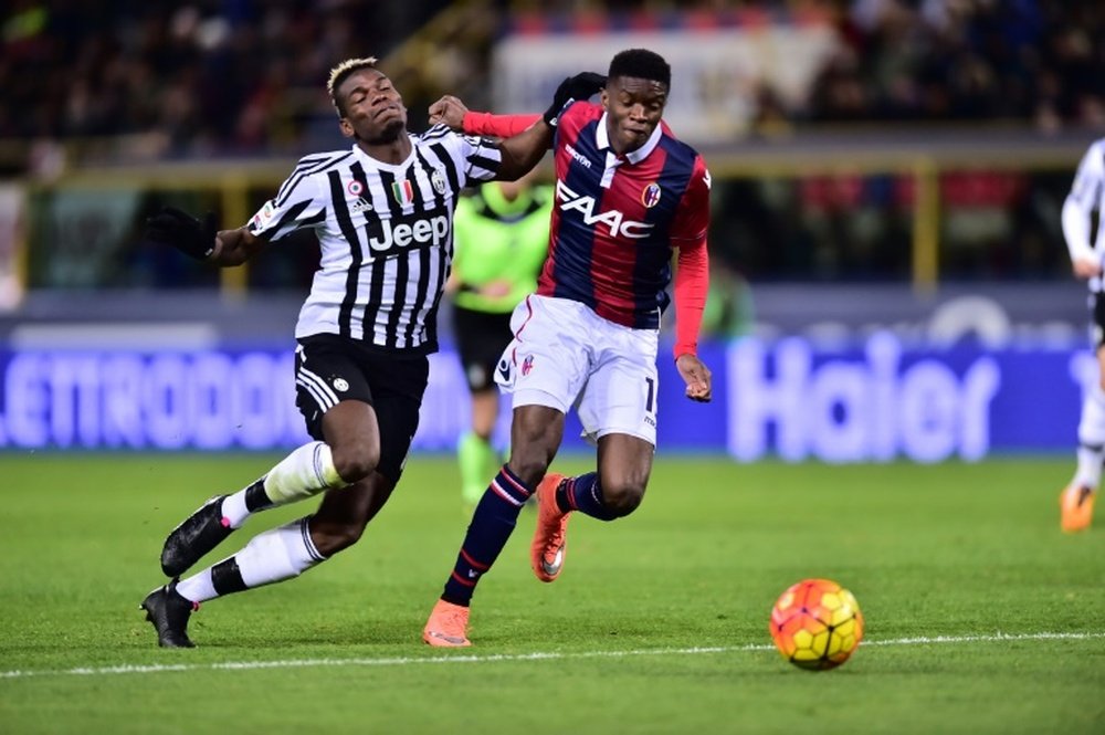 Juventus midfielder Paul Pogba (L) fights for the ball with Bolognas defender Ibrahima Mbaye during the Italian Serie A football match in Bologna on Febrauary 19, 2016