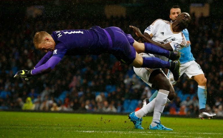 Manchester Citys goalkeeper Joe Hart dives to clear in front of Swansea Citys striker Bafetimbi Gomis