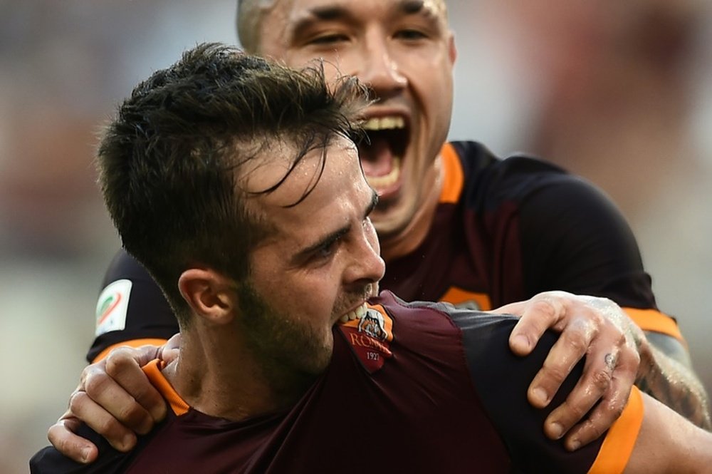 Romas midfielder Miralem Pjanic celebrates with teammate Radja Nainggolan (top) after scoring during an Italian Serie A football match against Juventus on August 30, 2015 at the Olympic stadium in Rome