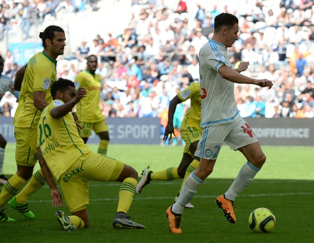 Marseilles French midfielder Florian Thauvin (R) dribbles past Nantes defenders. BeSoccer