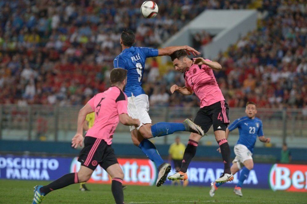 Italys Graziano Pelle (C) fights for the ball with Scotlands Russell Martin (R) at the National Stadium in TaQali, Malta on May 29, 2016