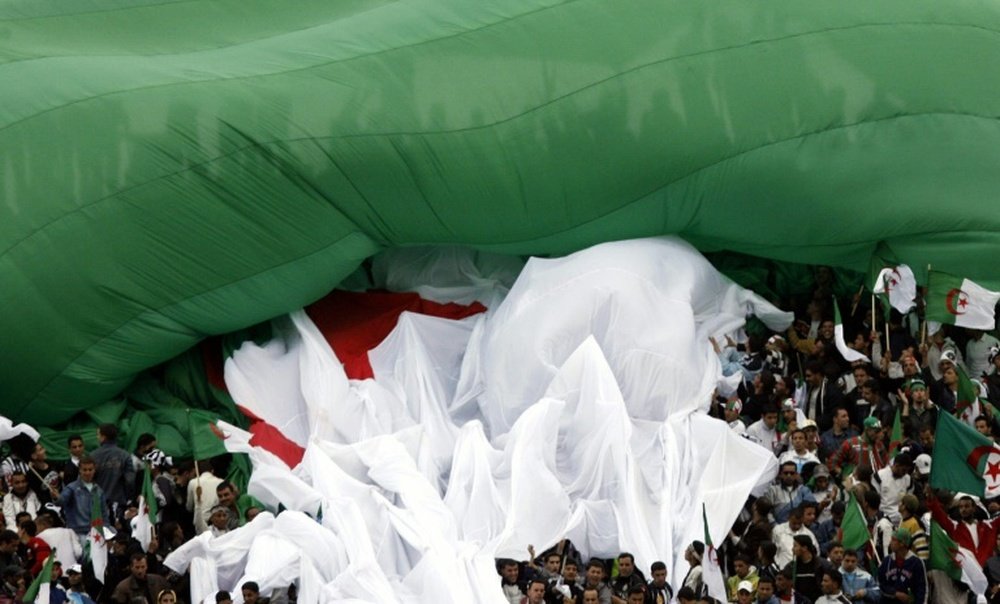 Fans of Algerian team Entente Setif hold a national flag as they cheer their team on May 3, 2007 in Setif