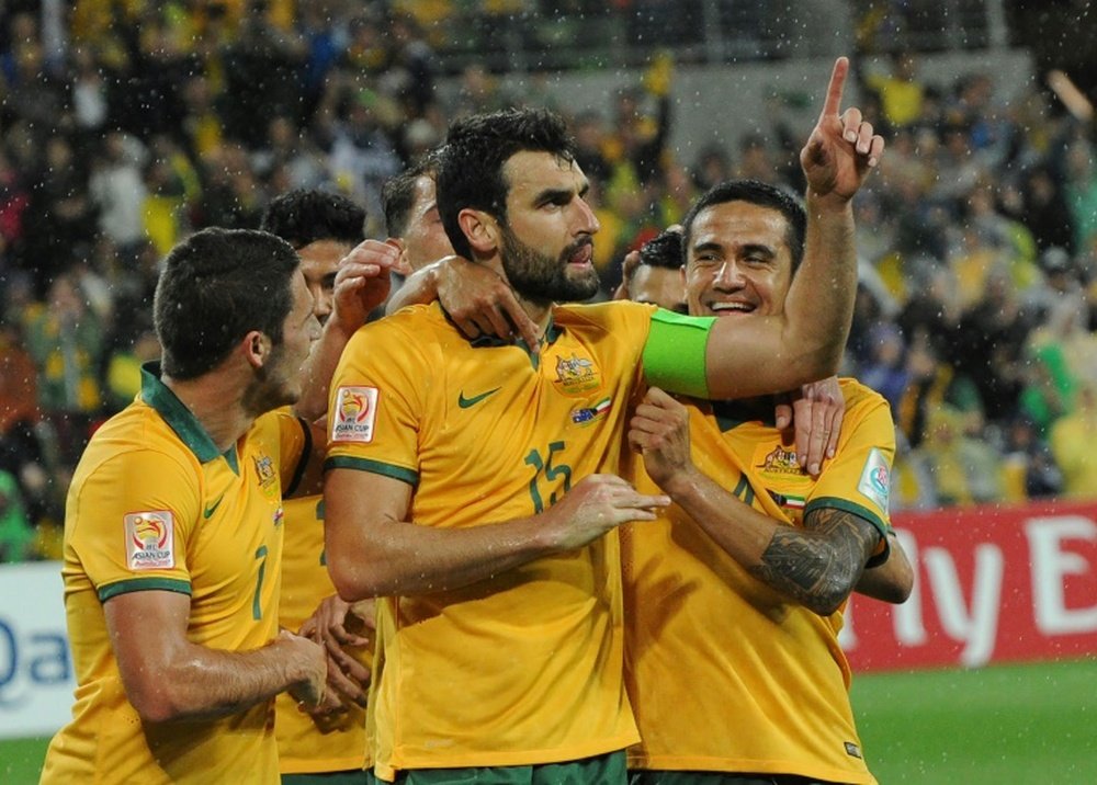 Australias Mile Jedinak (C) is congratulated by teammates Mathew Leckie (L) and Tim Cahill during the Asian Cup match against Kuwait in Melbourne on January 9, 2015