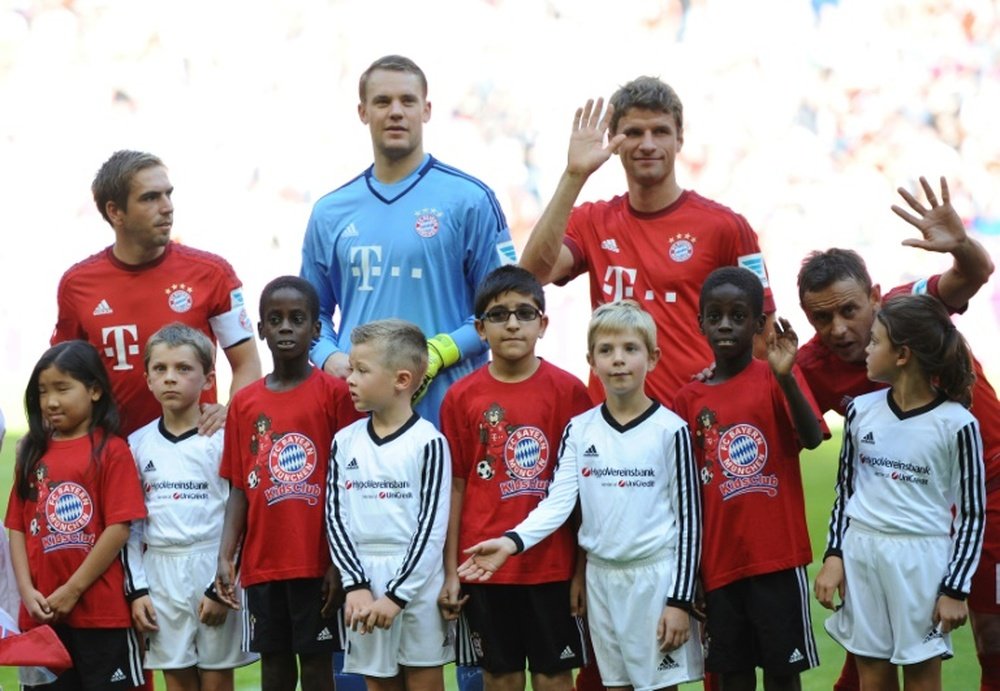 (L-R) Bayern Munichs defender Philipp Lahm, Manuel Neuer and Thomas Mueller stand with migrant children (in red) prior to the German first division Bundesliga football match FC Bayern Munich v FC Augsburg, in Munich on September 12, 2015