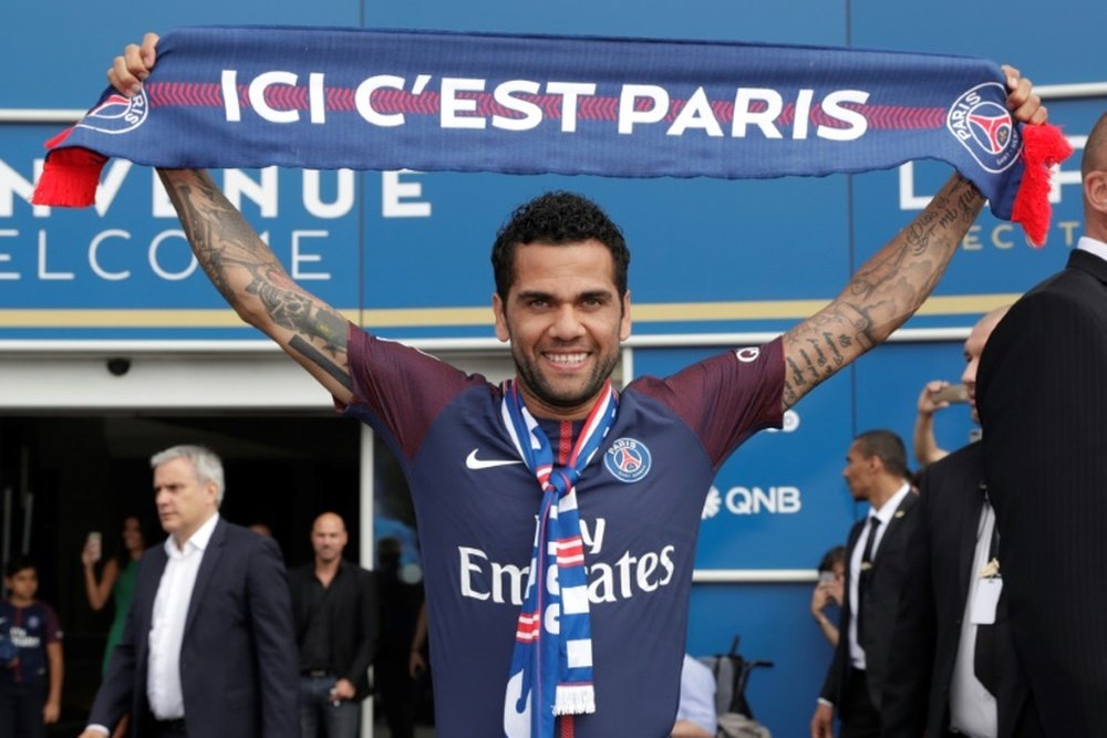 Paris Saint Germain's (PSG) new Brazilian defender Dani Alves poses with a scarf after a press conference on July 12, 2017, in Paris