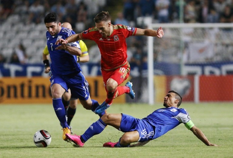 Aaron Ramsey (C) of Wales slips past a tackle from Cyprus Constantinos Charalambides during their EURO 2016 qualifying match in Nicosia on September 3, 2015