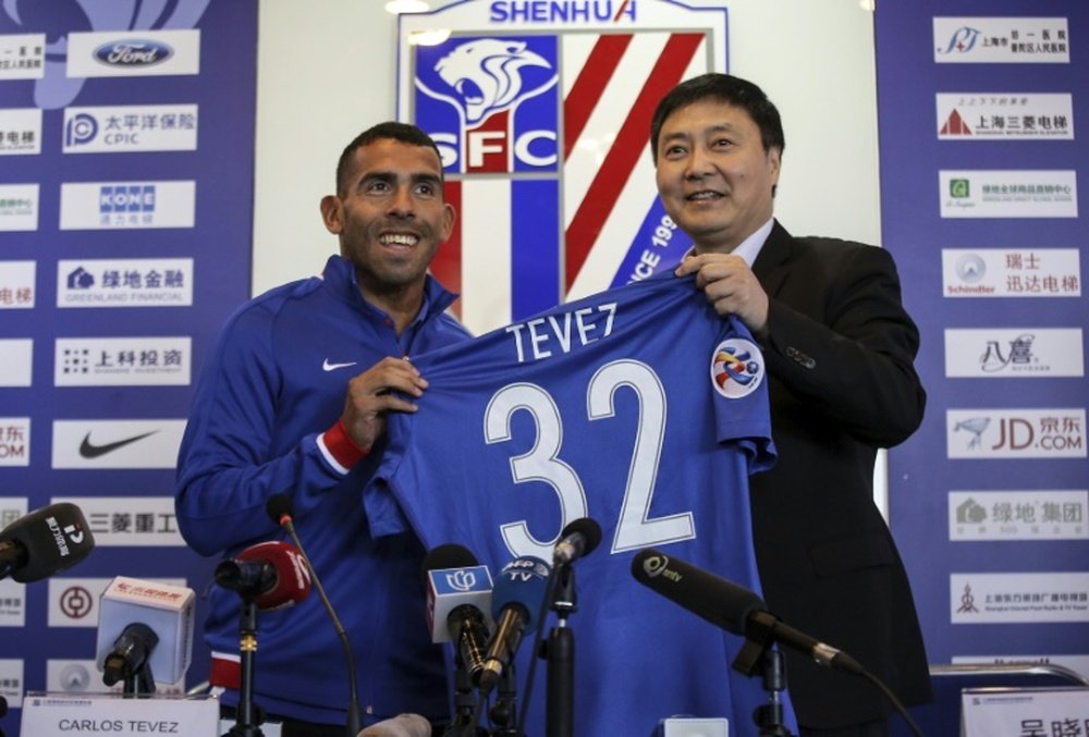 Argentine striker Carlos Tevez (L) poses with his No. 32 shirt of his new club Shanghai Shenhua. AFP