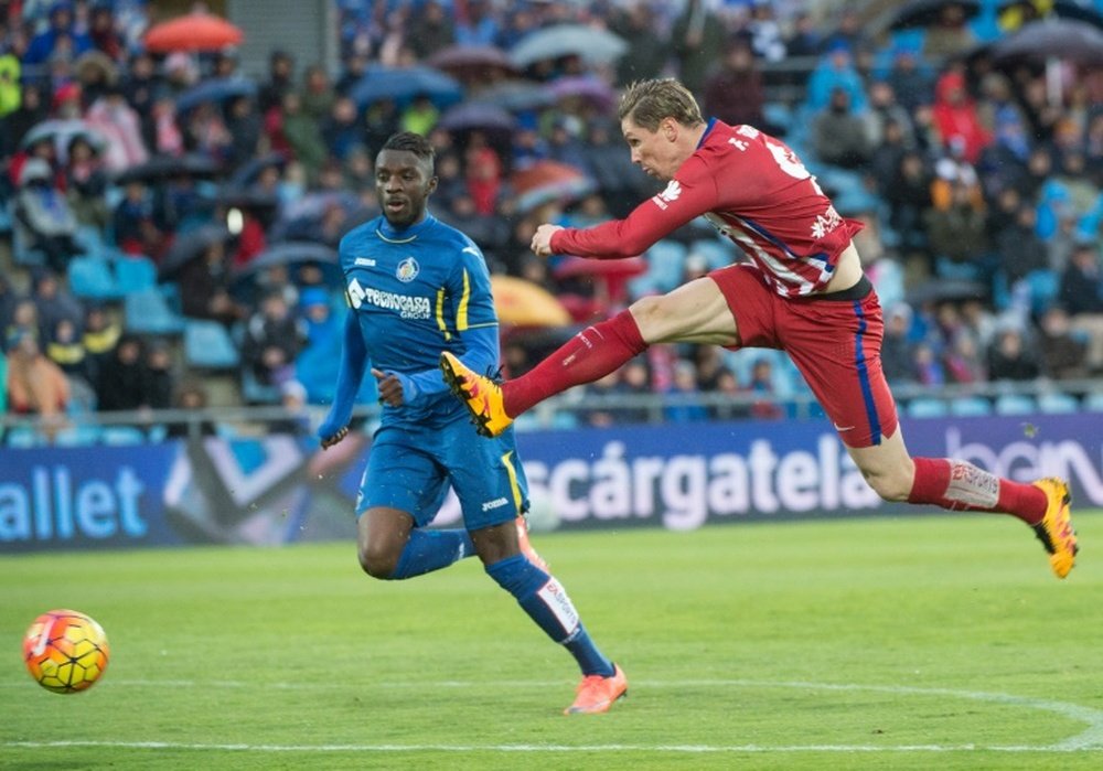 Atletico Madrids forward Fernando Torres (R) kicks the ball next to Getafes midfielder Karim Abdoul Yoda during a Spanish league football match on February 14, 2016