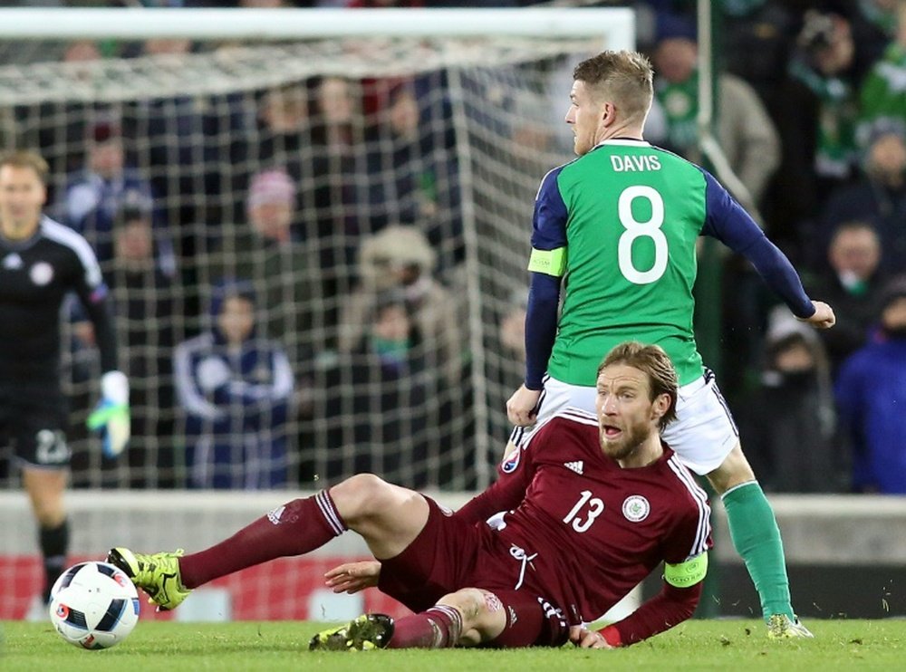 Northern Irelands midfiedler Steven Davis (R) vies with Latvias defender Kaspars Gorkss (floor) during the international friendly football match between Northern Ireland and Latvia at Windsor park in Belfast on November 13, 2015