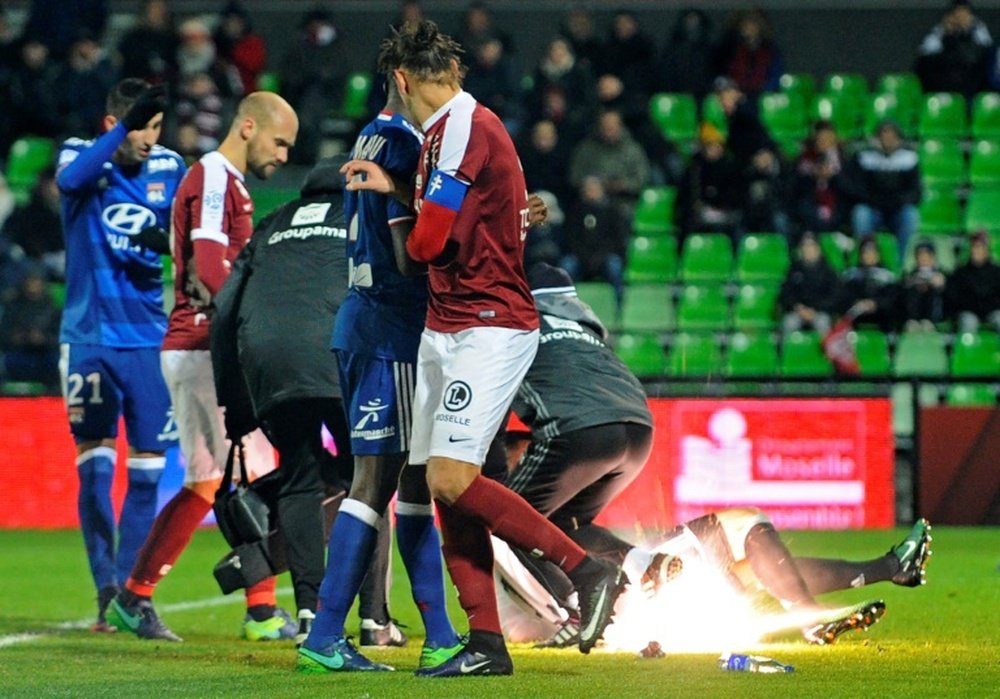 Players reacting as supporters throw a firecracker on the pitch during the French L1 football match between Metz and Lyon on December 3, 2016