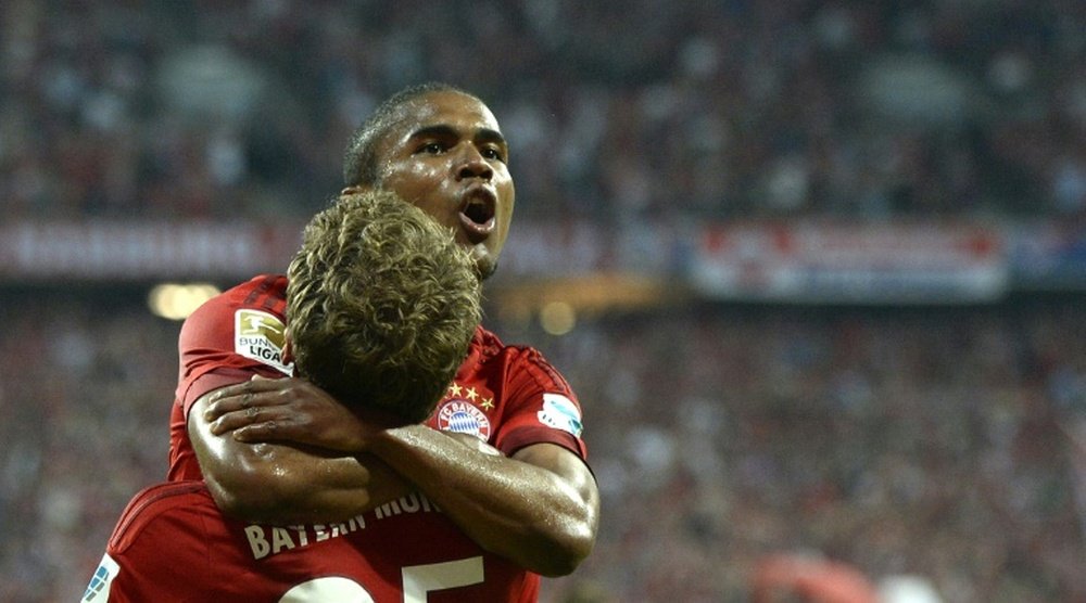 Bayern Munichs midfielder Douglas Costa (L) and striker Thomas Mueller celebrate during a German first division Bundesliga football match against Hamburg at the Allianz Arena in Munich, southern Germany, on August 14, 2015