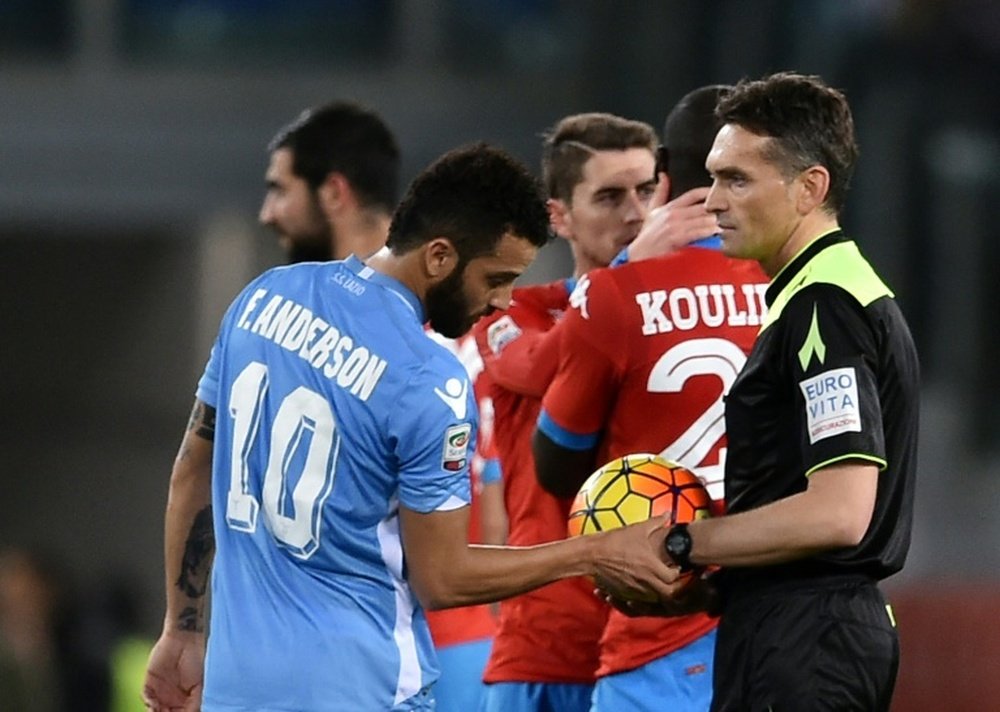 Lazios midfielder Felipe Anderson looks at the watch of referee Massimiliano Irrati (R) after he suspended the game due to racist chants during the Italian Serie A football match Lazio vs Napoli on February 3, 2016 at Olympic stadium in Rome