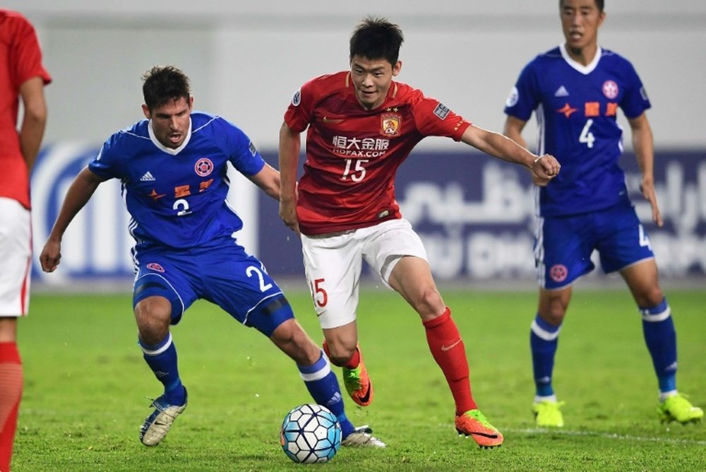 Zheng Wenzhao (C) of Guangzhou Evergrande competes for the ball with Josh Mitchell of Eastern FC dur