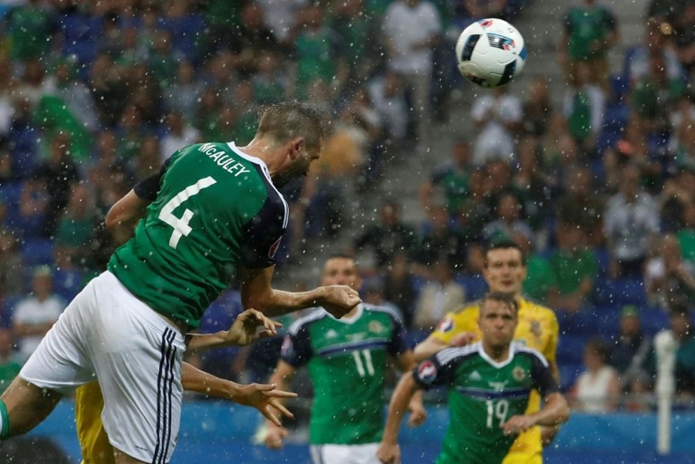 Northern Ireland defender Gareth McAuley (L) scores the opening goal against Ukraine. BeSoccer