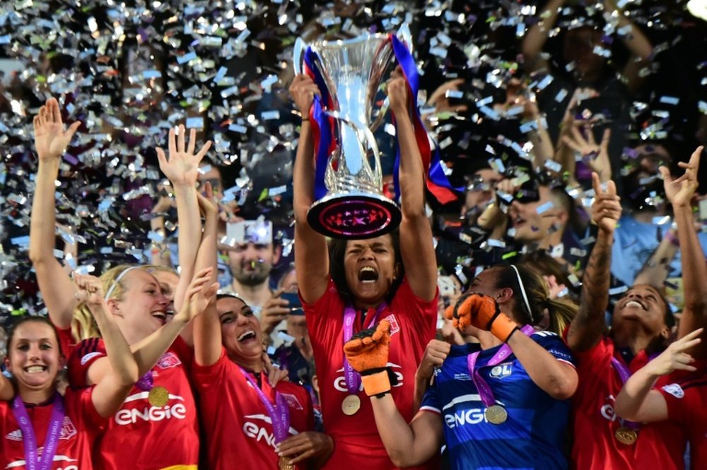 Olympique Lyonnais captain Wendie Renard holds the trophy to celebrate with teammates after winning the UEFA Womens Champions League Final football match VFL Wolfsburg vs Lyon in Reggio Emilia, Italy on May 26, 2016