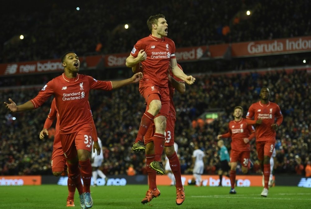 James Milner (C) celebrates next to Jordon Ibe (L) after scoring the opening goal from the penalty spot during the English Premier League football match between Liverpool and Swansea City in Liverpool on November 29, 2015