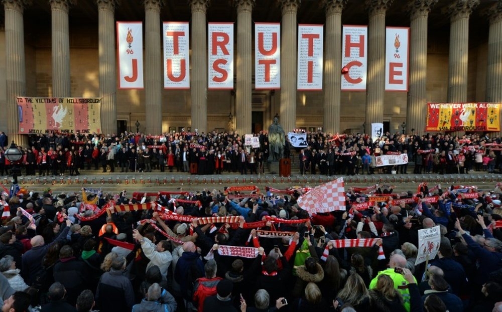 People hold up Liverpool scarves and sing Youll Never Walk Alone outside St Georges Hall. BeSoccer