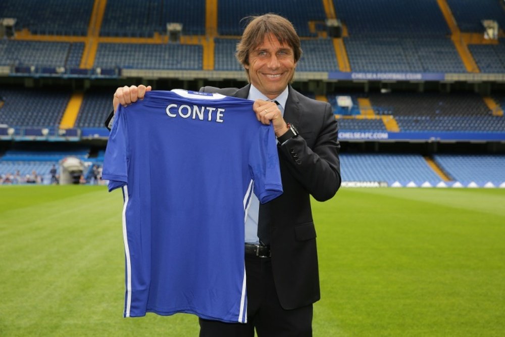 Chelseas newly appointed Italian manager Antonio Conte holds a Chelsea football shirt as he poses for photographs on the pitch at the clubs Stamford Bridge stadium in London on July 14, 2016