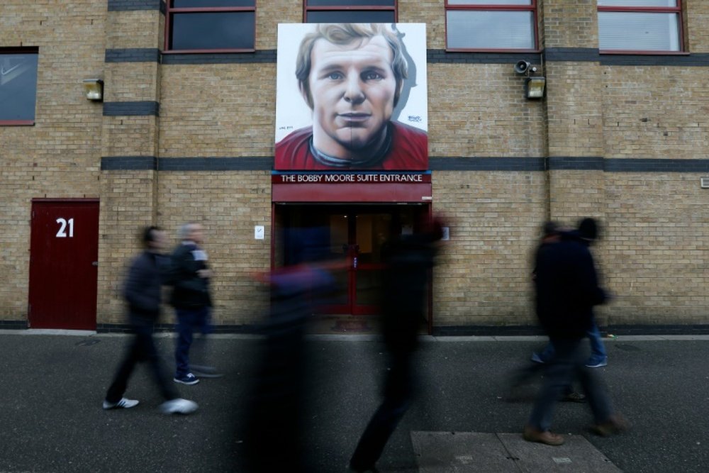 Supporters walk past new artwork of club legend Bobby Moore outside the ground, ahead of the English Premier League football match between West Ham United and Sunderland at The Boleyn Ground in Upton Park, in east London on February 27, 2016